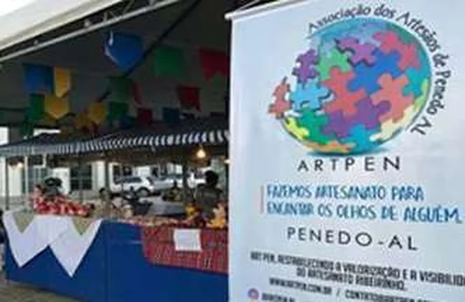Bancas com peças de artesanato e o painel da ART PEN ao fundo