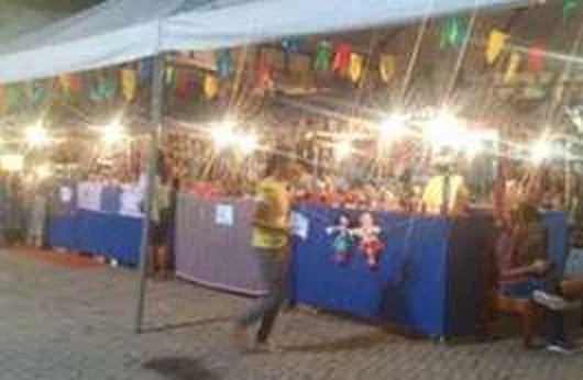 Feira de artesanato iluminada à noite, sob as tendas